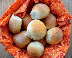 a bunch of bread rolls sitting in a basket on top of a table with an orange cloth