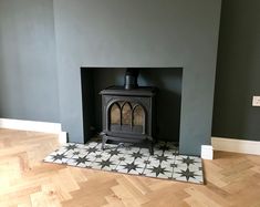 a wood burning stove sitting inside of a living room next to a wooden flooring