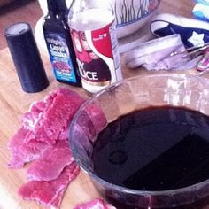 a bowl of black liquid sitting on top of a wooden table next to other items