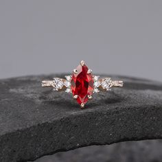 a close up of a ring with a red stone in the middle and two white diamonds around it