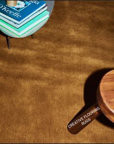 a wooden table sitting on top of a brown carpet next to a pile of books