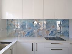 a kitchen with white cabinets and marble backsplash in the backround area