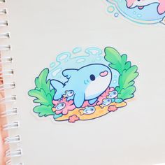 a hand holding a notebook with stickers on it and an image of a dolphin in the water