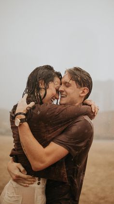 a man and woman hugging each other in the rain