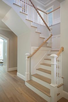 a white staircase with wooden handrails in a home's entryway area