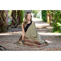 a woman sitting on the ground with a blanket over her