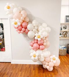 balloons are arranged in the shape of a letter on a wooden floor next to a white wall