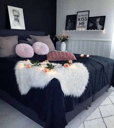 a black and white bedroom with flowers on the bed, candles in the air and pictures above it