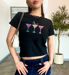 A flight of pink-toned martinis make this shirt an instant classic.  These signature cocktails are perfect for an updated downtown girl fit.  This illustrated design is printed on a shirt designed to be styled as a short and fitted top.  It's giving 90s and early 2000s baby tee. Refer to the size chart for to achieve your preferred fit.  This design is also available on a classic-fit unisex tee. PRODUCT DETAILS .: Made with 100%, midweight (5.3 oz/yd² (180 g/m US cotton that feels soft to the touch and a great choice for any season. .: Fabric blends: Heather colors - 50% cotton, 50% polyester,  Sport Grey - 90% cotton, 10% polyester. .: Shirt is Gildan model 5000B, a classic, crew neck style .:Tear-away label for scratch-free wear .: Made using ethically grown and harvested US cotton. PROD 2000s Baby, Downtown Girl Aesthetic, Signature Cocktails, Pink Martini, Polyester Shirt, Downtown Girl, Girl Fits, Fitted Top, Signature Cocktail