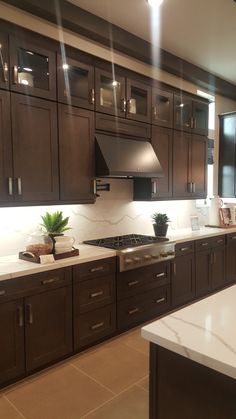 a kitchen with dark wood cabinets and white counter tops is lit by recessed lighting