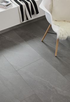 a white chair sitting on top of a gray floor next to a table with a black and white blanket