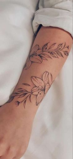 a woman's arm with flowers and leaves tattooed on the left side of her arm