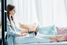 a woman sitting on a bed using a laptop computer