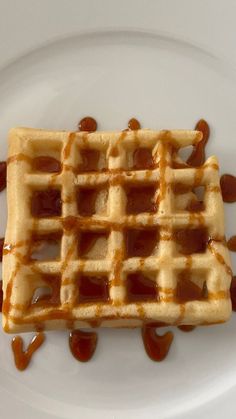 a waffle covered in syrup on a white plate