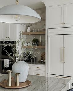 a kitchen with white cabinets and marble counter tops, an island in the foreground