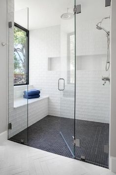 a bathroom with a walk in shower next to a white tiled wall and black floor