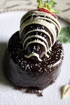 a chocolate cake with white frosting and a strawberry on top is sitting on a plate