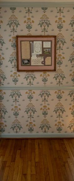 an empty room with wood floors and wallpaper on the walls, framed by a wooden frame