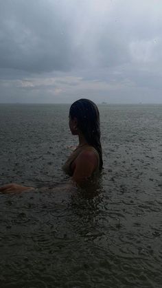 a woman is sitting in the water with her back to the camera