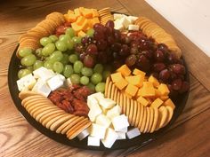 a platter filled with cheese, crackers and grapes