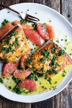 a white plate topped with fish covered in sauce and garnished with parsley