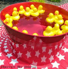 a red bucket filled with yellow rubber ducks on top of a checkered table cloth