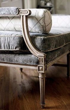 an antique style bench with pillows on it in front of a mirror and wooden floor