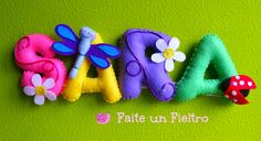 the word love spelled out in felt letters with flowers and bugs on them against a green background