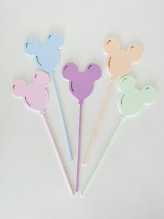 four mickey mouse shaped cake toppers in pastel colors