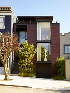 two story houses with trees and bushes on the sidewalk