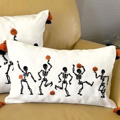 two pillows with skeletons and pumpkins on them sitting on a couch next to each other