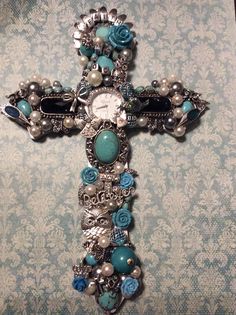 a cross made out of beads and other items on a wallpapered background with blue flowers