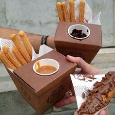 two people holding up some food in front of each other with dipping sauces on them