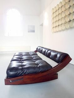 a black leather futon bed sitting on top of a white floor