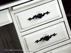 a white dresser with black handles and knobs