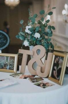 a table topped with pictures and flowers next to a wooden amp sign that says & u