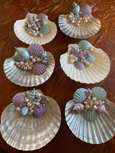 four seashells with shells and pearls on them are sitting on a table top