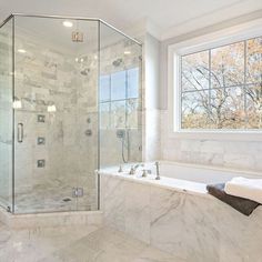 a bathroom with a large tub and walk - in shower next to a window on the wall