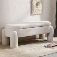 a white bench sitting on top of a carpeted floor next to a potted plant