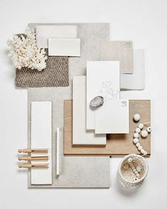 an assortment of white and beige items on a wooden tray, including notebooks, papers, beads, and flowers