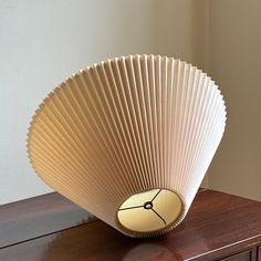 a fan shaped object sitting on top of a wooden table next to a wall in a room