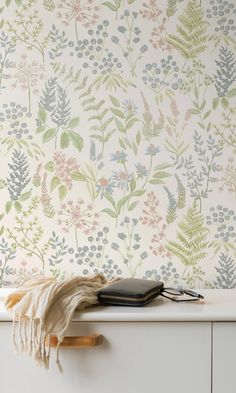 a wallpapered with flowers and plants on it is next to a white dresser