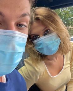 two people wearing face masks while sitting in a car