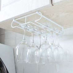 several wine glasses hanging from a rack in a kitchen