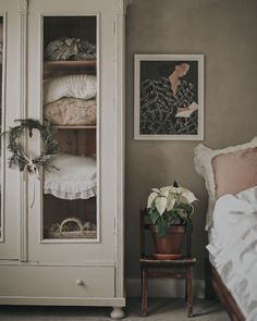 a white armoire sitting next to a bed in a room with pictures on the wall