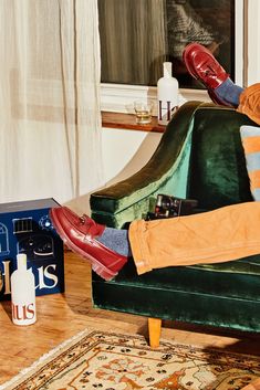 a person sitting on a green chair with their feet up in the air and wearing red shoes