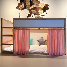 a bunk bed with pink curtains and a wooden star hanging on the wall above it