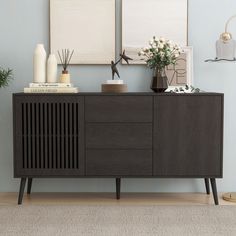 a wooden sideboard with two vases on top of it next to a wall