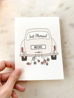 a hand holding up a card with an image of a car on it that says just married