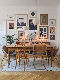 a dining room table with chairs and pictures on the wall above it, surrounded by candles